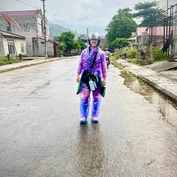 Conor in a rain poncho on a wet street while travelling